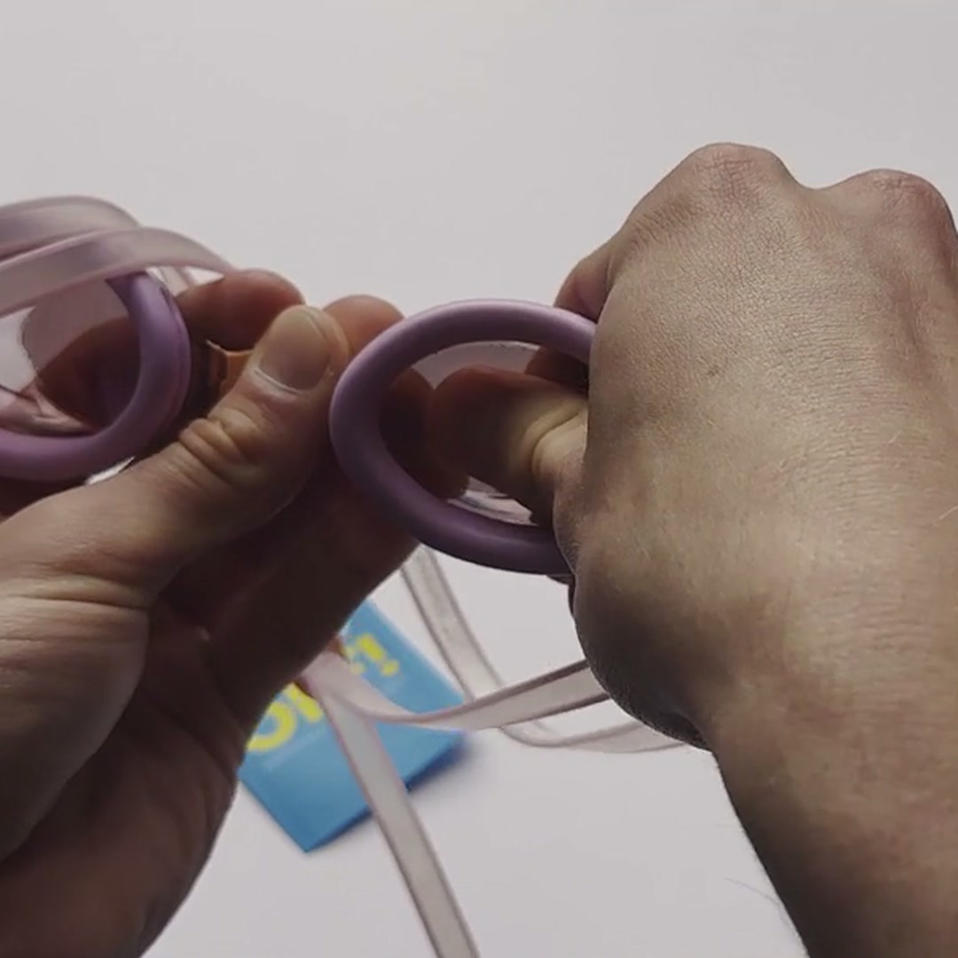 Pressing a clear FOG OFF! anti-fog patch onto the inside of a swim goggle lens